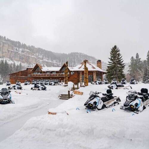 Spearfish Canyon Lodge in winter snowmobiles sitting on snow 